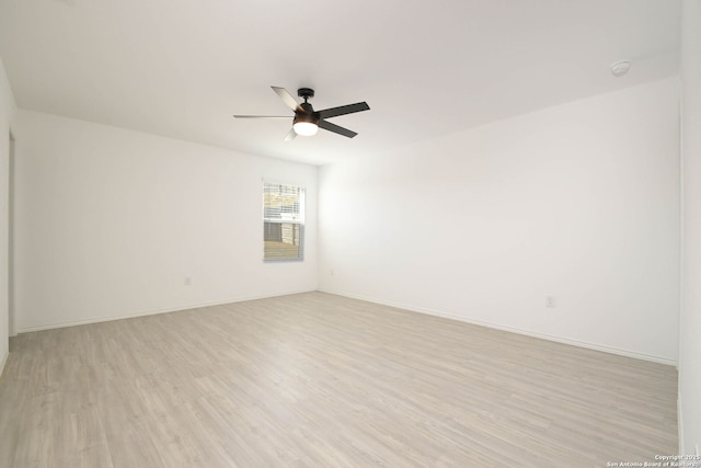 spare room featuring a ceiling fan, baseboards, and light wood finished floors