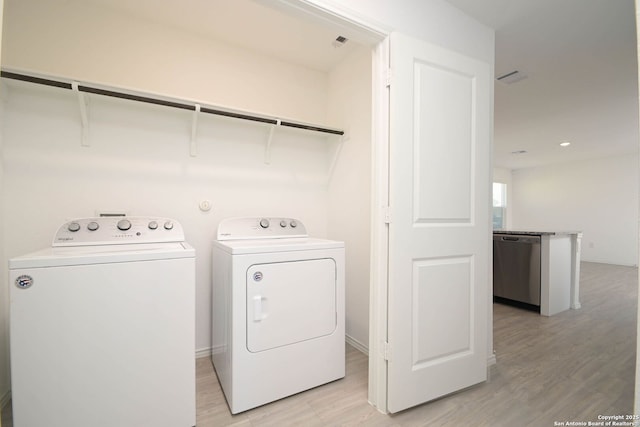 laundry area featuring light wood-type flooring, laundry area, baseboards, and washer and clothes dryer