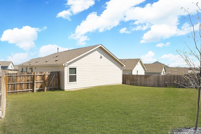 rear view of house with a lawn and a fenced backyard