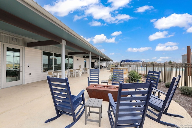 view of patio with outdoor dining space, fence, and a fire pit