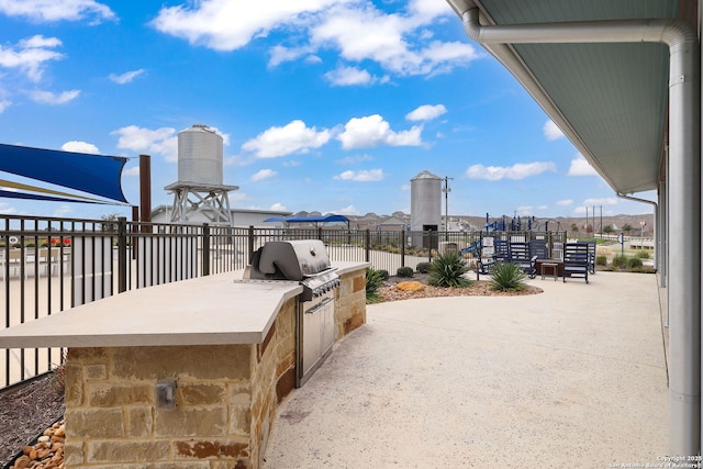 view of patio with exterior kitchen, fence, and area for grilling