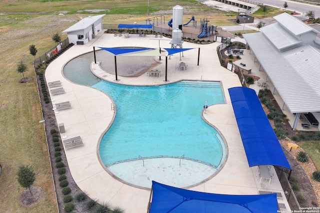 community pool featuring a water slide, fence, and a patio