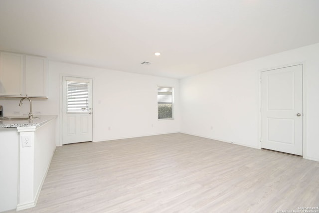 interior space featuring light wood finished floors, a sink, visible vents, and baseboards