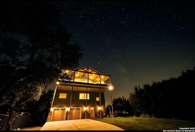 view of front of home featuring a garage, concrete driveway, a lawn, and a balcony