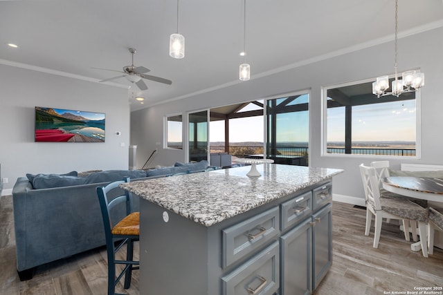 kitchen featuring ornamental molding, a center island, a water view, gray cabinets, and light wood-type flooring