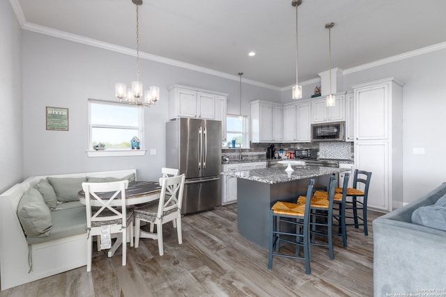 kitchen with a breakfast bar area, stainless steel appliances, wood finished floors, open floor plan, and decorative backsplash