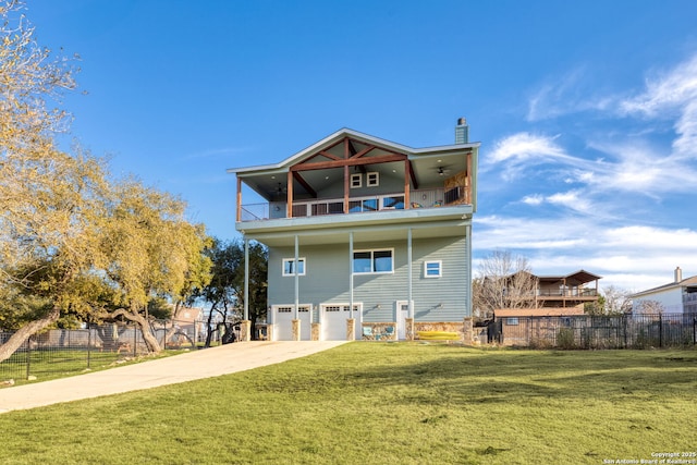 back of house featuring a balcony, fence, driveway, a lawn, and a chimney