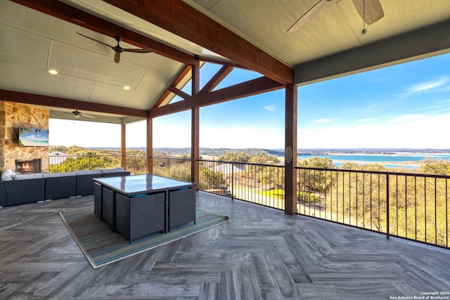 deck featuring a water view, an outdoor living space with a fireplace, a jacuzzi, and a ceiling fan