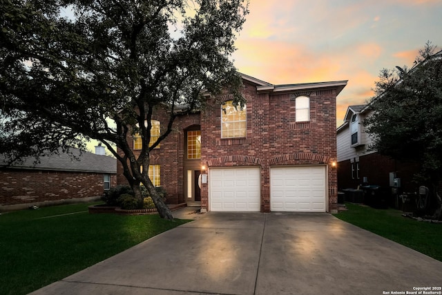 traditional-style house featuring a yard, concrete driveway, brick siding, and an attached garage