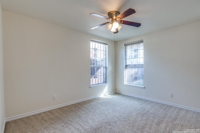 carpeted spare room featuring ceiling fan and baseboards