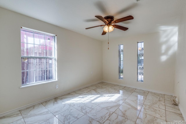 unfurnished room with marble finish floor, baseboards, and a ceiling fan