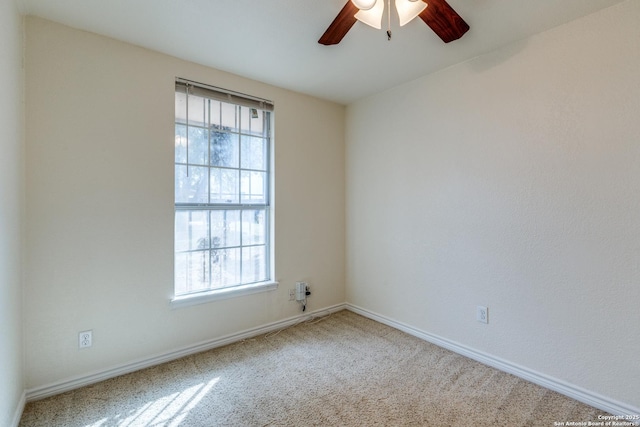 carpeted spare room with a ceiling fan and baseboards