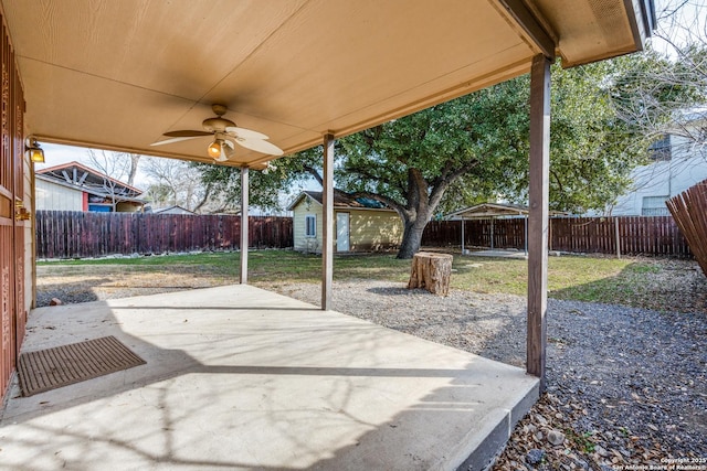 view of patio featuring an outbuilding, a fenced backyard, and a ceiling fan