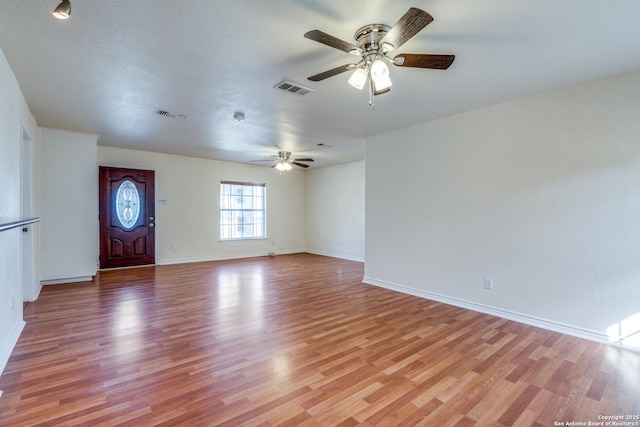 interior space featuring light wood-style floors, baseboards, visible vents, and a ceiling fan