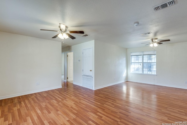 empty room featuring ceiling fan, light wood-type flooring, and visible vents