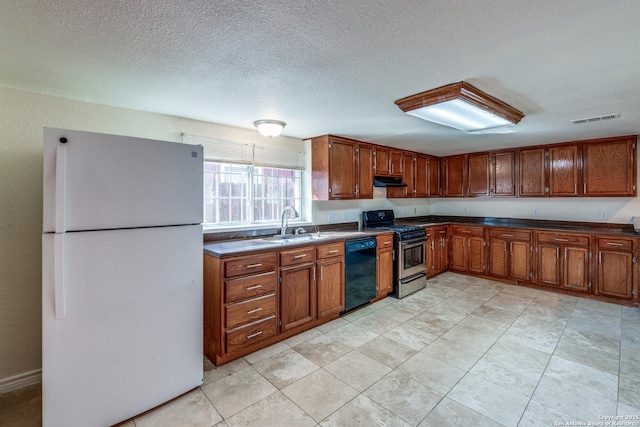 kitchen featuring under cabinet range hood, visible vents, black dishwasher, freestanding refrigerator, and stainless steel gas stove