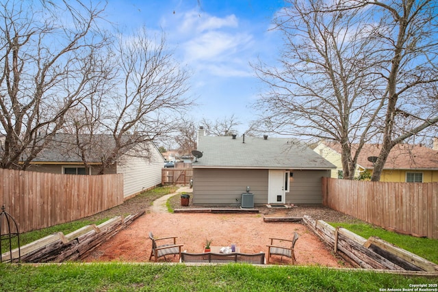 rear view of property featuring central air condition unit, a garden, a chimney, and a fenced backyard