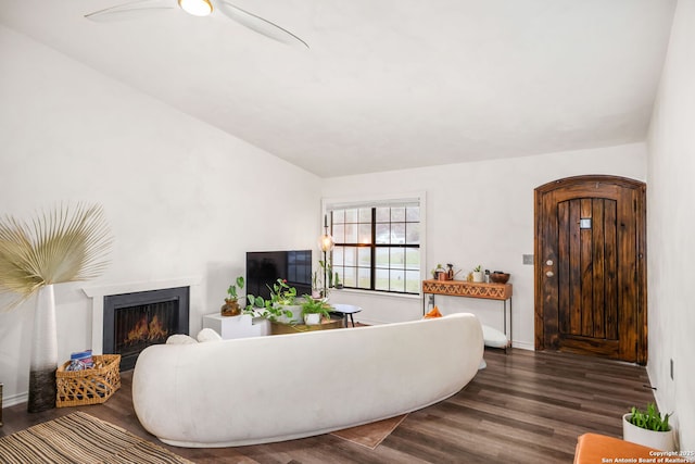 living area with lofted ceiling, a lit fireplace, ceiling fan, and wood finished floors