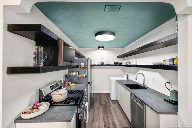 kitchen featuring open shelves, dark countertops, stainless steel appliances, and separate washer and dryer