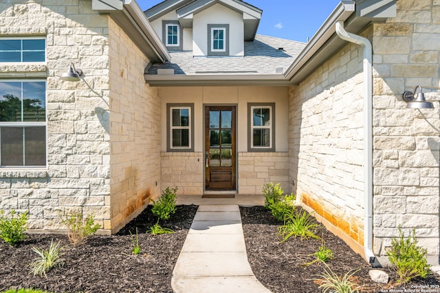 property entrance with a shingled roof and stone siding