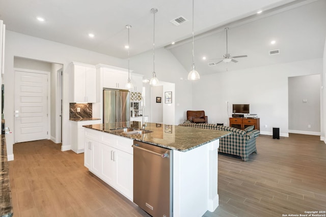 kitchen featuring light wood finished floors, visible vents, dark stone counters, appliances with stainless steel finishes, and a sink