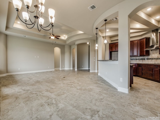 unfurnished living room featuring a ceiling fan, a tray ceiling, visible vents, and arched walkways