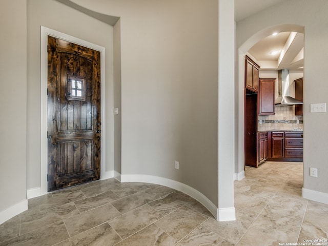 foyer entrance featuring arched walkways and baseboards