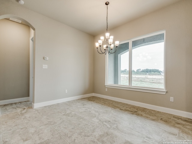 spare room with arched walkways, a notable chandelier, and baseboards