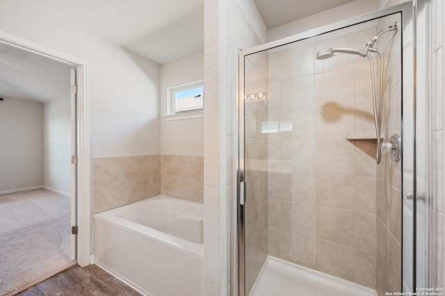 bathroom with a shower stall, a bath, and wood finished floors