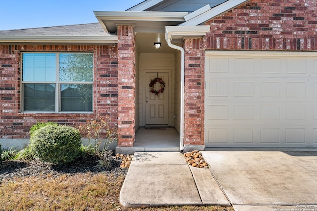 view of exterior entry featuring a garage, brick siding, and roof with shingles