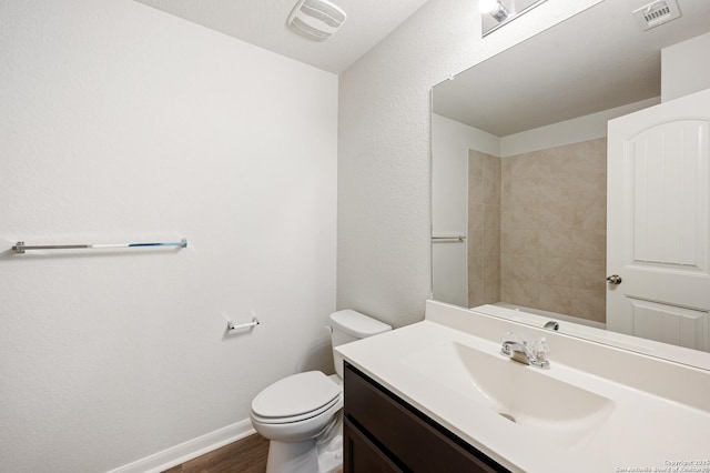 bathroom with toilet, vanity, visible vents, and baseboards