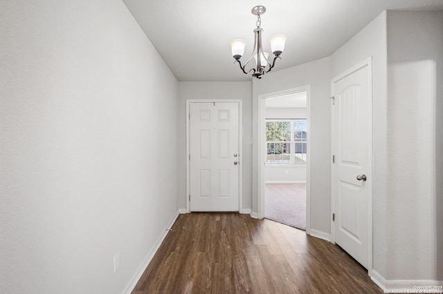 interior space featuring dark wood-type flooring, a chandelier, and baseboards