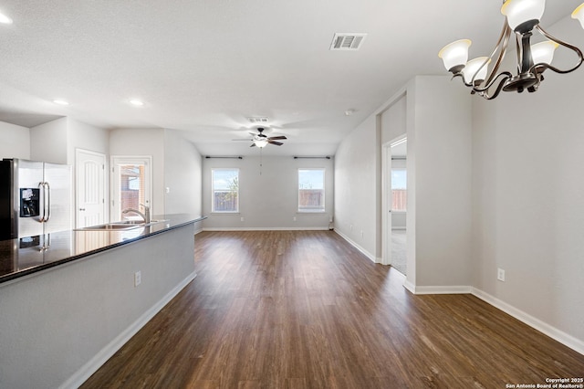 unfurnished living room with baseboards, visible vents, dark wood-type flooring, a sink, and ceiling fan with notable chandelier