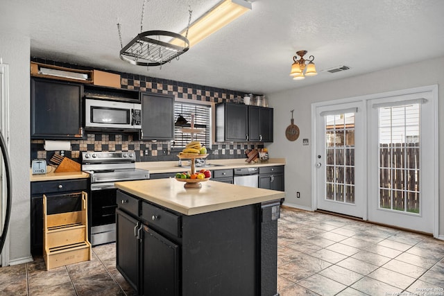 kitchen featuring tasteful backsplash, visible vents, light countertops, appliances with stainless steel finishes, and dark cabinets