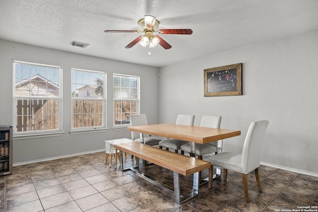 dining room with a textured ceiling, plenty of natural light, visible vents, and baseboards