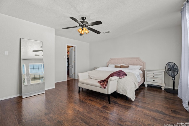 bedroom featuring a textured ceiling, ceiling fan, wood finished floors, visible vents, and a walk in closet