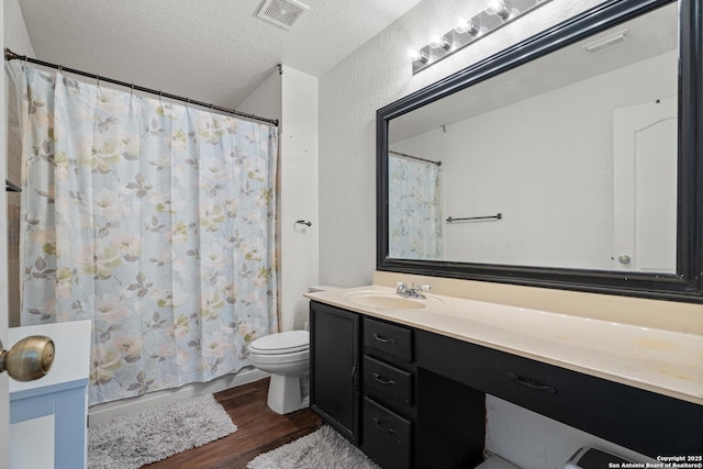 full bathroom featuring visible vents, a textured ceiling, toilet, and wood finished floors