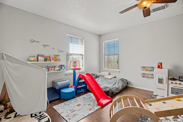 bedroom with a textured ceiling, visible vents, wood finished floors, and a textured wall