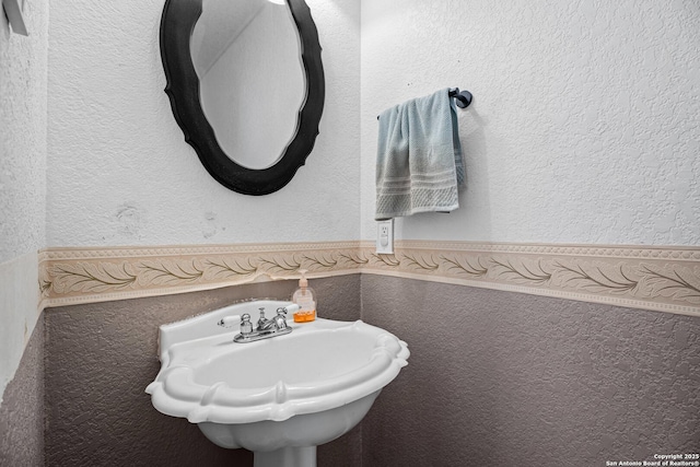 bathroom with a textured wall and a sink