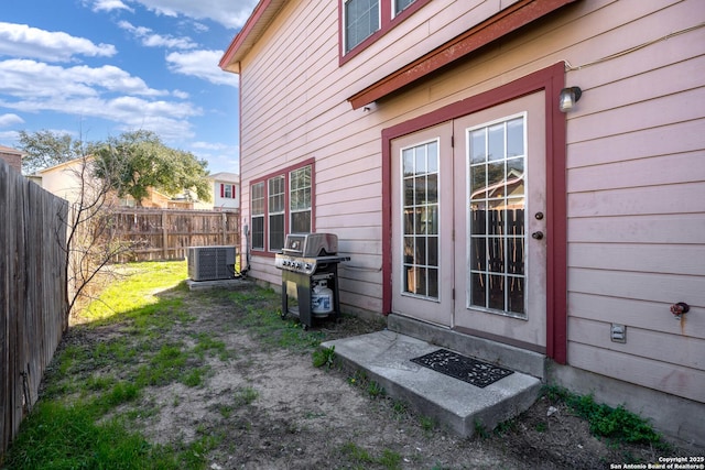 entrance to property featuring fence, central AC, and french doors