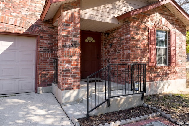 view of exterior entry featuring a garage, crawl space, and brick siding