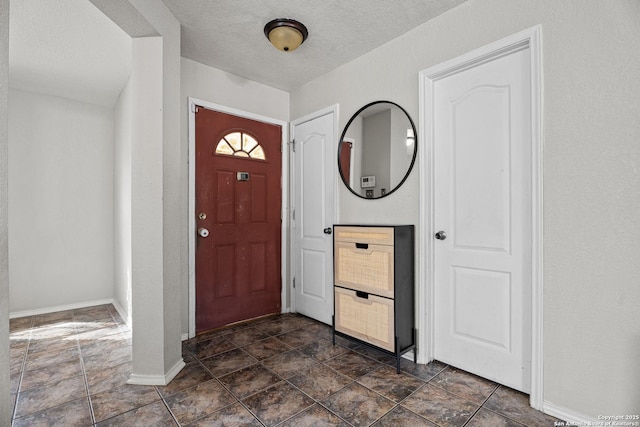 foyer entrance featuring a textured ceiling and baseboards