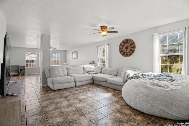 living area featuring ceiling fan, a textured ceiling, and a wealth of natural light