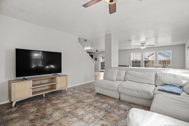 living area featuring baseboards, a ceiling fan, and a textured ceiling