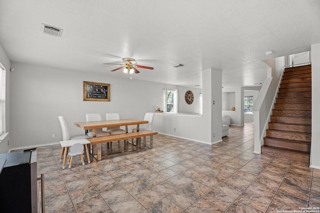 dining space featuring visible vents, a textured ceiling, and stairs