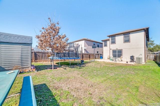 view of yard with a trampoline, an outbuilding, a fenced backyard, and a storage shed