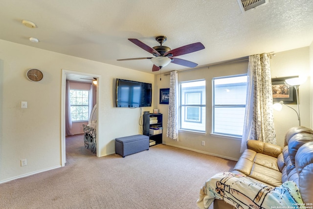 carpeted living room with a textured ceiling, ceiling fan, visible vents, and baseboards