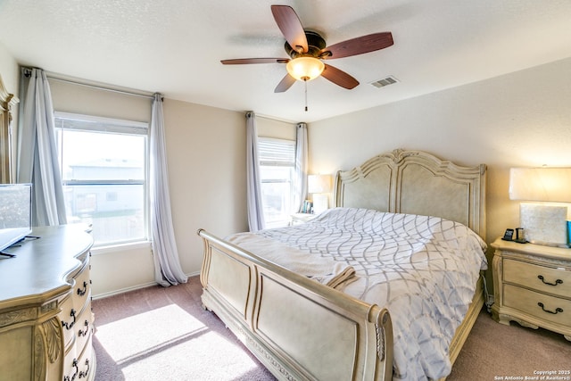 bedroom with multiple windows, visible vents, a ceiling fan, and light colored carpet