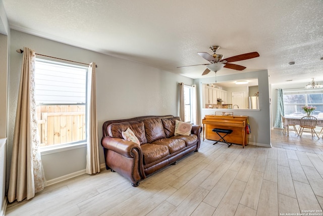 living room with a textured ceiling, a wealth of natural light, and light wood-style floors