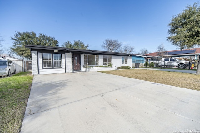 single story home featuring driveway, a front lawn, fence, and brick siding